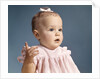 1960s baby girl wearing pink dress with a bow in her hair pointing a finger by Anonymous