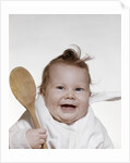 1960s 1970s smiling baby wearing bib and holding wooden spoon by Anonymous