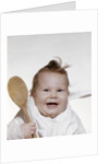 1960s 1970s smiling baby wearing bib and holding wooden spoon by Anonymous