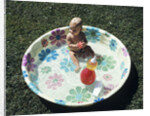 1970s baby sitting in plastic backyard kiddy pool viewed from above by Anonymous