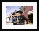 1960s cowboy sheriff with badge draws gun arrests gunfighter in front of livery stable by Anonymous