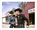 1960s cowboy sheriff with badge draws gun arrests gunfighter in front of livery stable by Anonymous