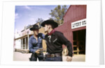 1960s cowboy sheriff with badge draws gun arrests gunfighter in front of livery stable by Anonymous