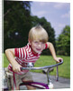 1970s 1960s smiling blond boy leaning over handlebars of bicycle looking at camera by Anonymous