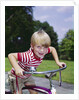 1970s 1960s smiling blond boy leaning over handlebars of bicycle looking at camera by Anonymous
