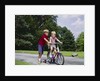 1960s 1970s boy helping little brother ride two wheel bicycle with training wheels by Anonymous