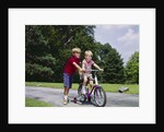 1960s 1970s boy helping little brother ride two wheel bicycle with training wheels by Anonymous