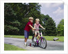 1960s 1970s boy helping little brother ride two wheel bicycle with training wheels by Anonymous