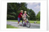 1960s 1970s boy helping little brother ride two wheel bicycle with training wheels by Anonymous