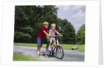 1960s 1970s boy helping little brother ride two wheel bicycle with training wheels by Anonymous
