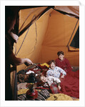 1960s father with lantern checking up on 3 boys in sleeping bags pajamas in tent by Anonymous