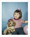 1950s 1960s little girl in party hat sitting holding a cocker spaniel puppy by Anonymous