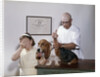 1960s little girl hiding eyes with as pet basset hound gets injection from veterinarian by Anonymous