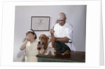 1960s little girl hiding eyes with as pet basset hound gets injection from veterinarian by Anonymous