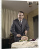 1960s man carving ham dinner looking at camera by Anonymous
