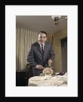 1960s man carving ham dinner looking at camera by Anonymous
