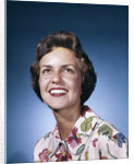 1960s smiling woman in white print dress looking up studio by Anonymous