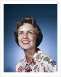 1960s smiling woman in white print dress looking up studio by Anonymous
