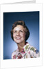 1960s smiling woman in white print dress looking up studio by Anonymous
