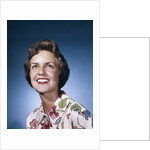 1960s smiling woman in white print dress looking up studio by Anonymous
