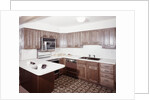1970s kitchen with dark wooden cabinets and a microwave oven over the stove by Anonymous