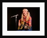 1970s blond young woman ponytails plaid shirt jeans play guitar singing microphone folk singer singers by Anonymous