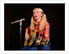 1970s blond young woman ponytails plaid shirt jeans play guitar singing microphone folk singer singers by Anonymous