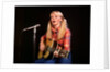 1970s blond young woman ponytails plaid shirt jeans play guitar singing microphone folk singer singers by Anonymous