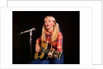 1970s blond young woman ponytails plaid shirt jeans play guitar singing microphone folk singer singers by Anonymous