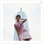 1960s young woman print miniskirt dress summer hat in front empire state building new york city by Anonymous