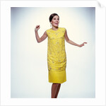 1960s smiling brunette woman modeling yellow sequined cocktail dress clothes by Anonymous