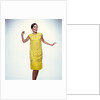 1960s smiling brunette woman modeling yellow sequined cocktail dress clothes by Anonymous