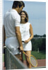 1970s smiling couple standing by net on tennis court holding wood rackets by Anonymous