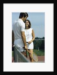 1970s smiling couple standing by net on tennis court holding wood rackets by Anonymous