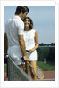 1970s smiling couple standing by net on tennis court holding wood rackets by Anonymous