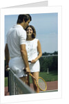 1970s smiling couple standing by net on tennis court holding wood rackets by Anonymous