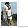 1970s smiling couple standing by net on tennis court holding wood rackets by Anonymous
