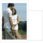 1970s smiling couple standing by net on tennis court holding wood rackets by Anonymous