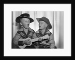 1950s 2 juvenile boys in cowboy hat & shirts playing ukulele & singing mouth open wide by Anonymous