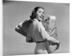 1950s smiling woman carrying grocery bags both hands looking at camera over her shoulder by Anonymous