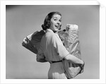 1950s smiling woman carrying grocery bags both hands looking at camera over her shoulder by Anonymous