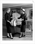 1950s woman in hat stole & gloves taking hatbox from saleswoman by Anonymous