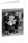 1950s woman in hat stole & gloves taking hatbox from saleswoman by Anonymous