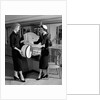 1950s woman in hat stole & gloves taking hatbox from saleswoman by Anonymous