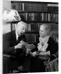 1930s 1940s retired senior couple looking at check in living room man smoking pipe by Anonymous