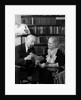 1930s 1940s retired senior couple looking at check in living room man smoking pipe by Anonymous