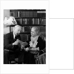 1930s 1940s retired senior couple looking at check in living room man smoking pipe by Anonymous