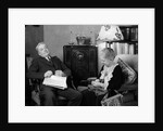 1930s elderly couple sitting in living room listening to radio woman knitting man with newspaper in lap by Anonymous