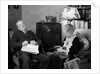 1930s elderly couple sitting in living room listening to radio woman knitting man with newspaper in lap by Anonymous