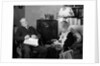 1930s elderly couple sitting in living room listening to radio woman knitting man with newspaper in lap by Anonymous